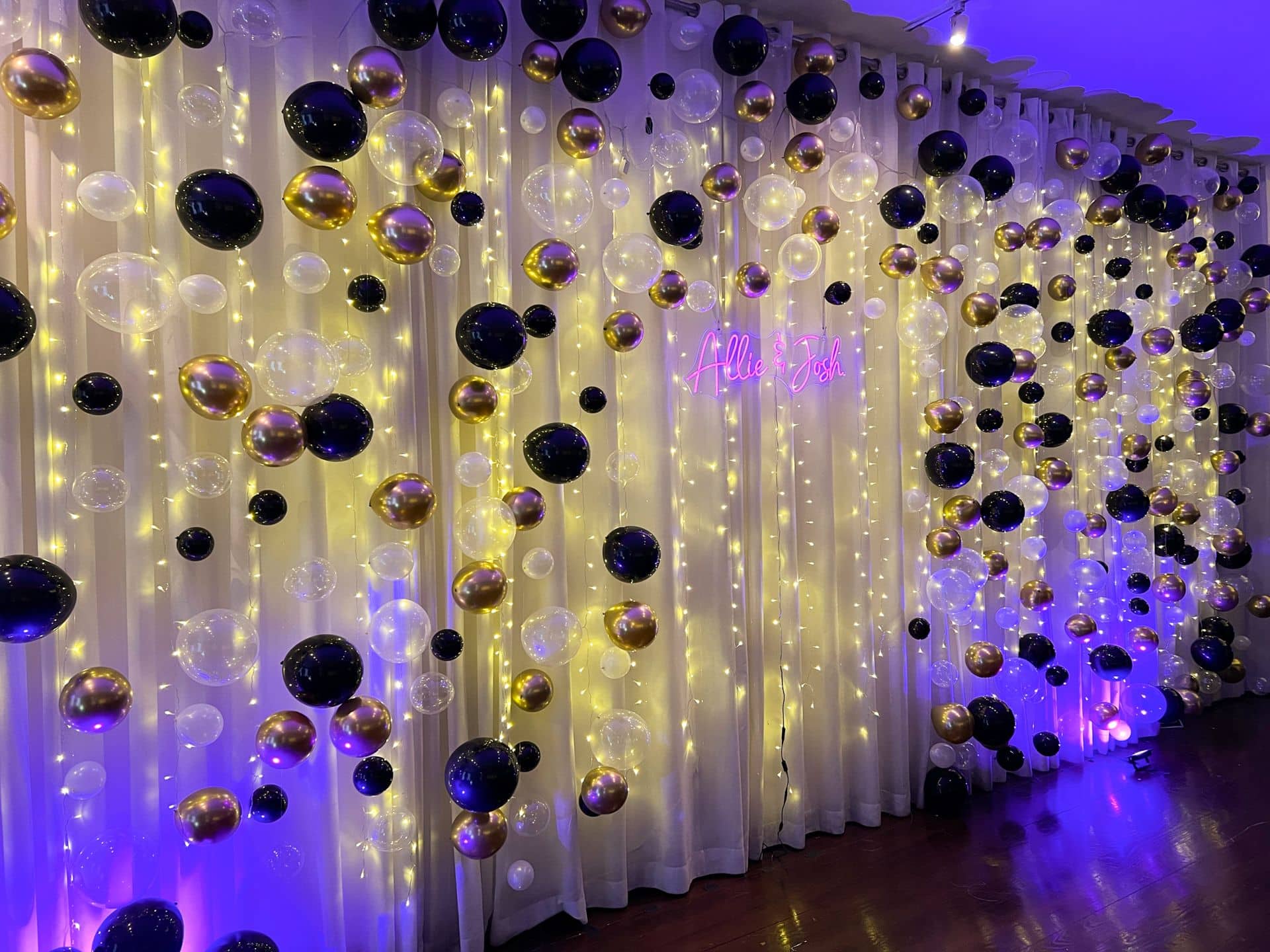 Black and Gold Balloon Bubble Wall with Twinkle Lights and Neon Sign for Engagement Party