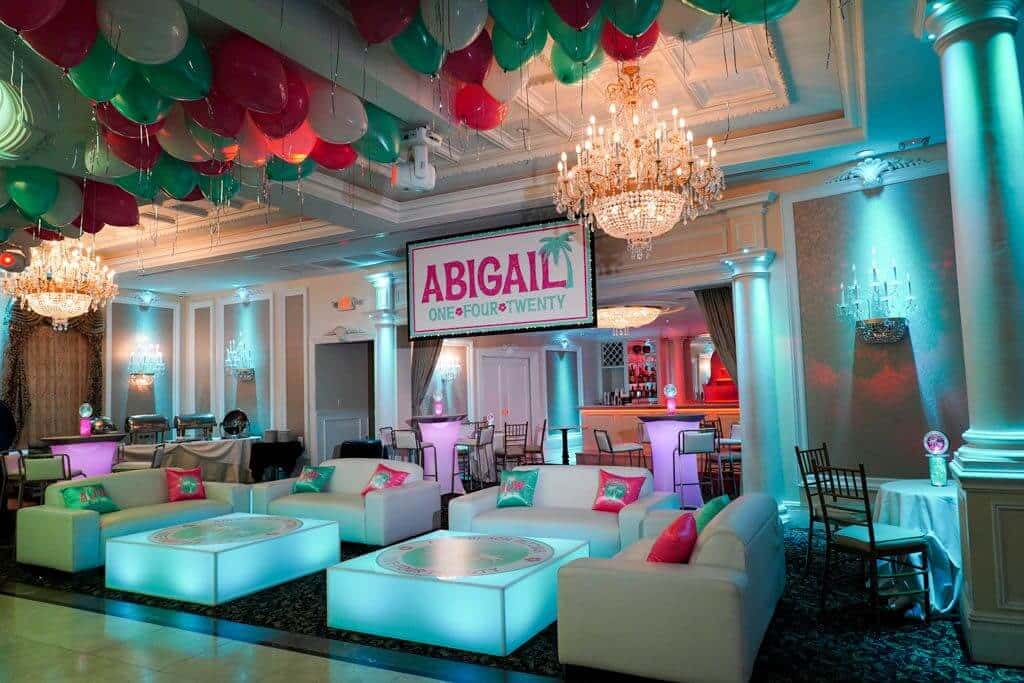 Tropical Themed Bat Mitzvah Lounge with Custom Logo Pillows and Glittered Backdrop at Primavera Regency, NJ
