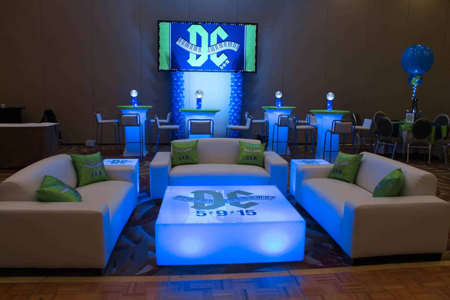 Custom Lounge Setup with Couches, LED Tables with Logo Decals, LED Hightops with Centerpieces and Logo Backdrop for Music Themed Bar Mitzvah at the Doubletree Tarrytown