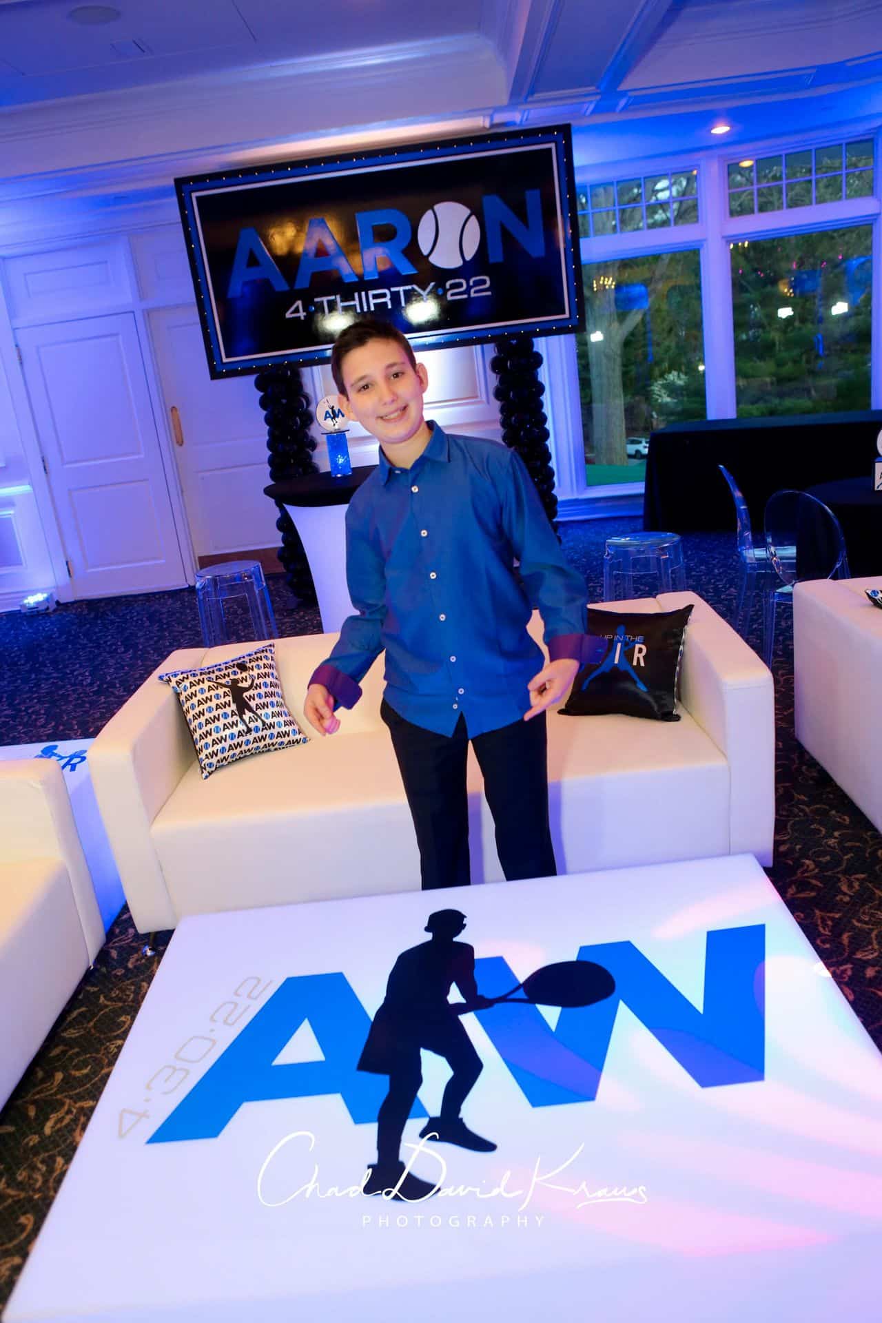 Tennis Themed Bar Mitzvah Lounge with Custom Logo Tables, Pillows and Backdrop at Scarsdale Golf Club