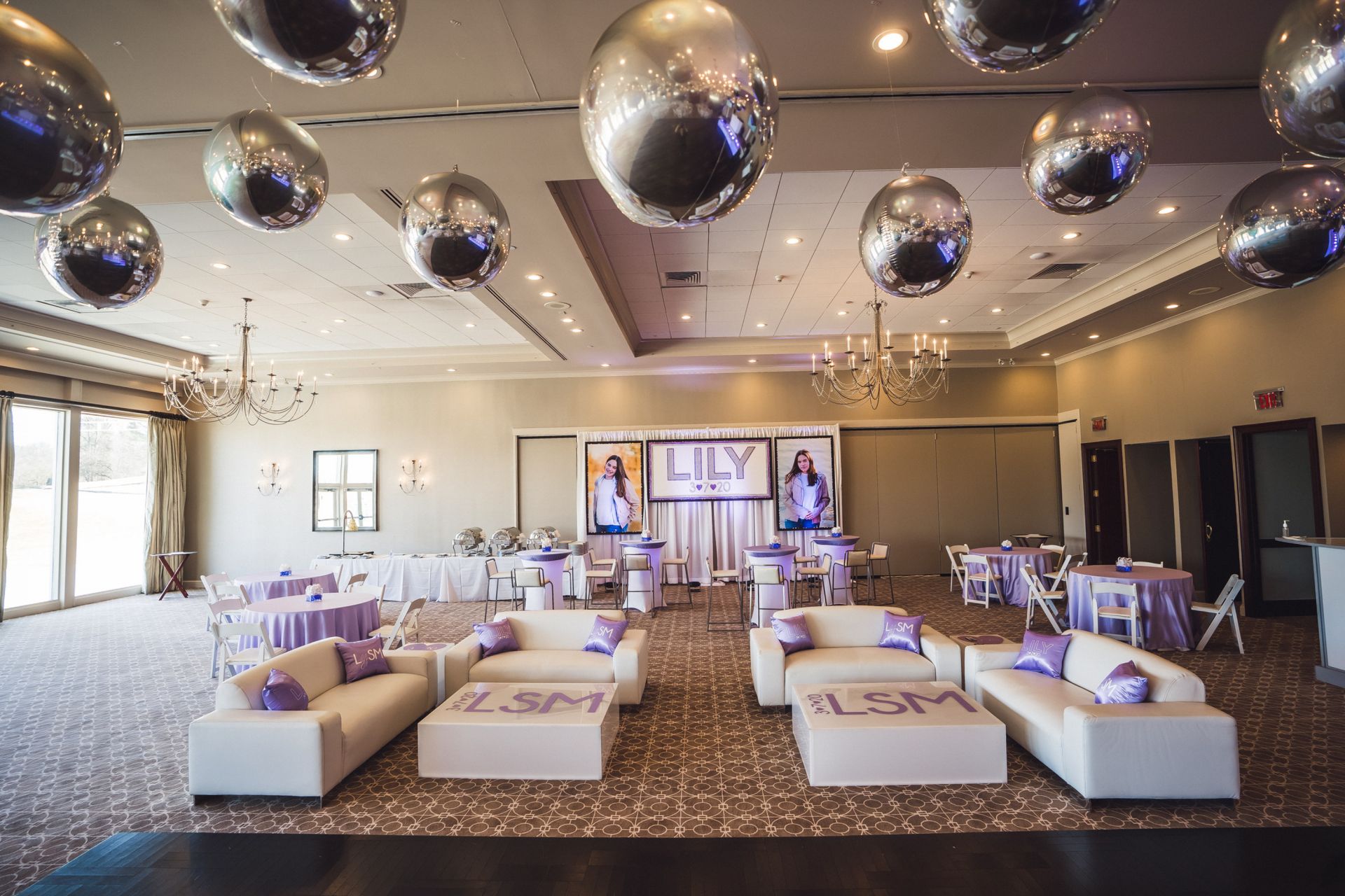 Beautiful Custom LED Lounge Furniture Setup with Couches, Custom Pillows, Custom Coffee Tables, High Top, Low Cocktail Tables, Metallic Silver Orbz Ceiling Treatment and Custom Backdrop and LED Blowup Pictures