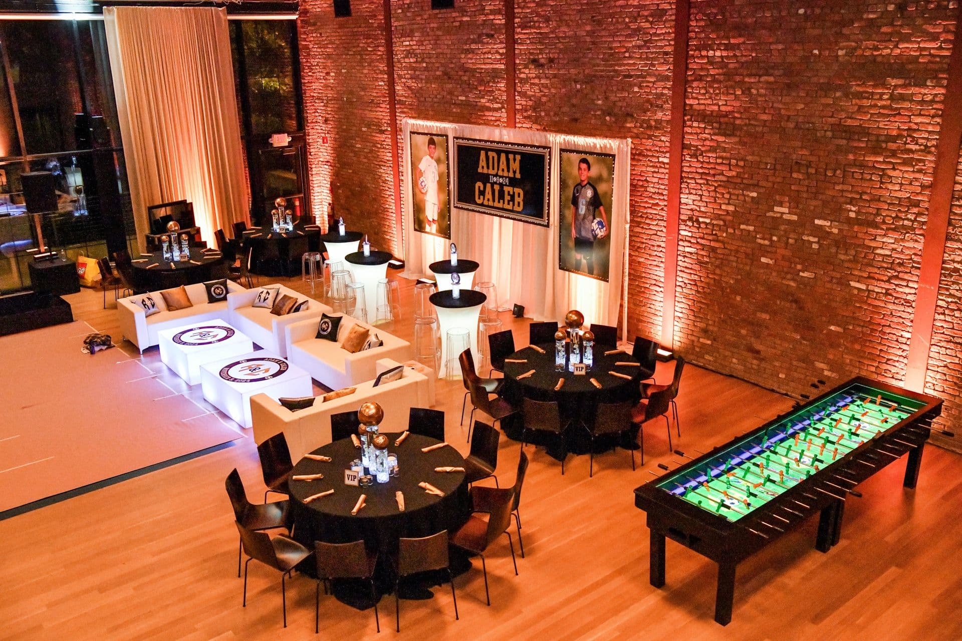 LED Orchid Centerpieces Topped with Gold Soccer Balls, Custom Lounge, Mini Logo Toppers, Hand Cut Backdrops on a Pipe and Drape and Orange Uplighting for a B'nai Mitzvah at The Roundhouse, Beacon
