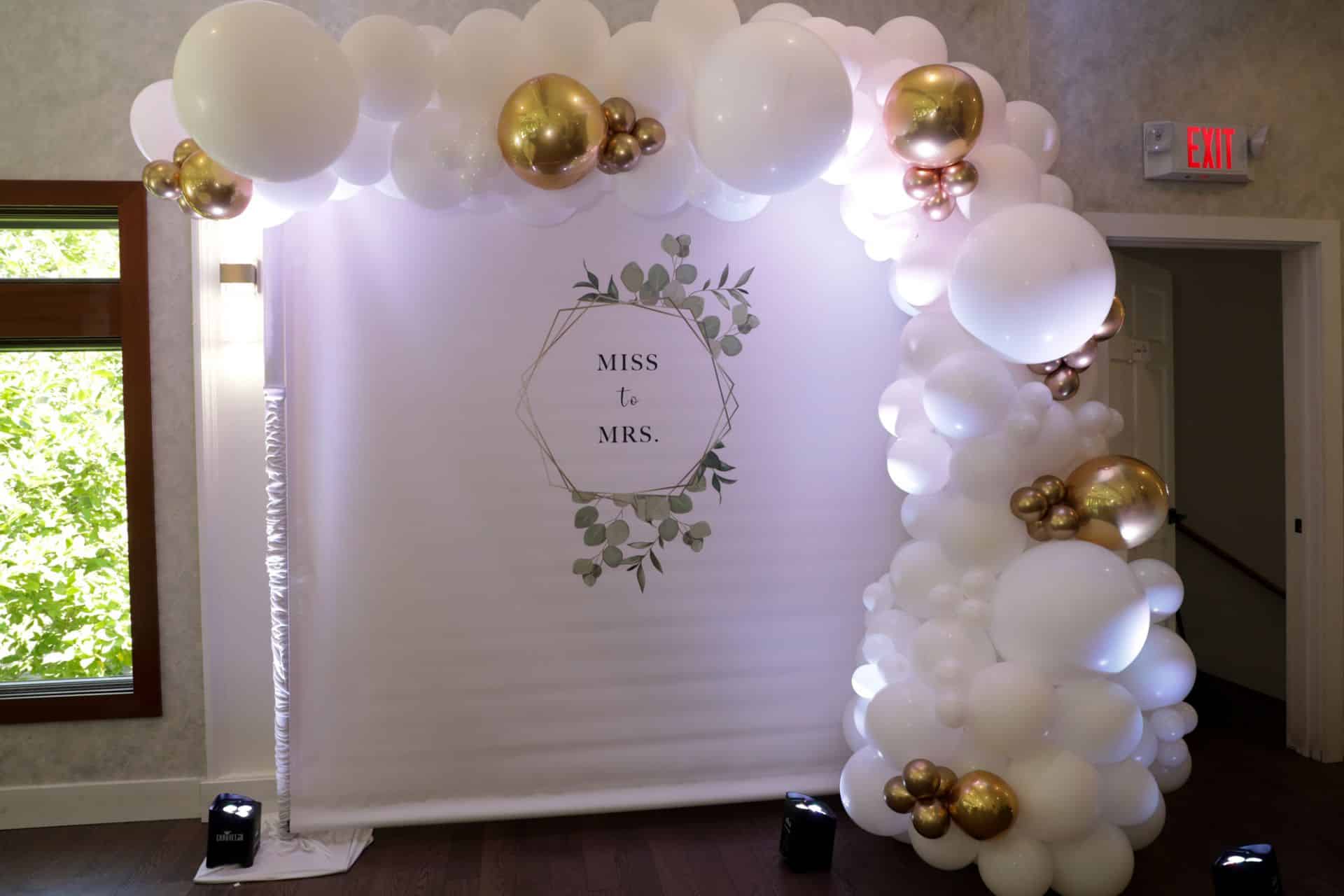 White and Gold Balloon Garland with Custom Vinyl Logo Backdrop for Bridal Shower at Dimoras